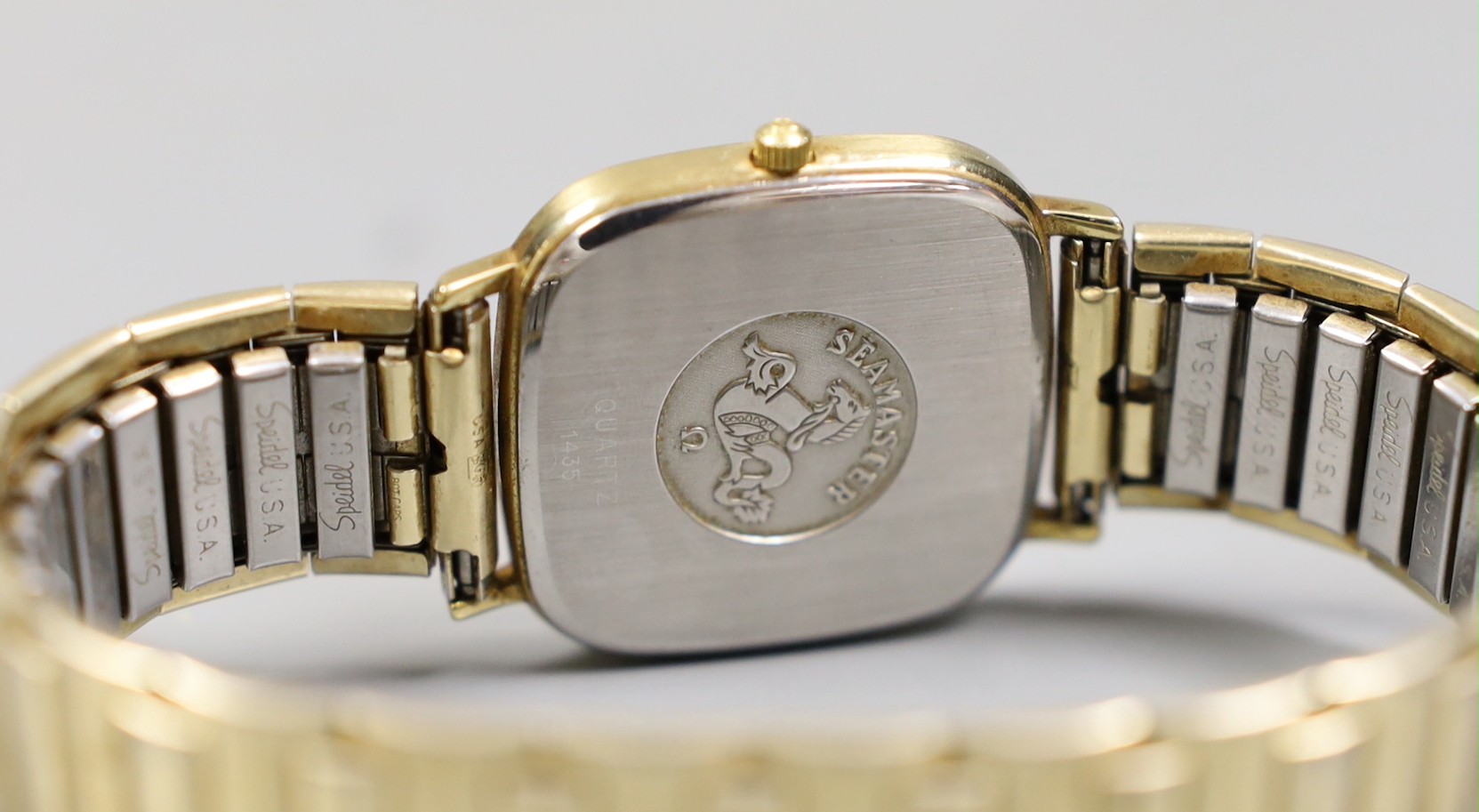 A gentleman's gold plated Omega Seamaster day/date quartz wrist watch, on associated flexible bracelet.